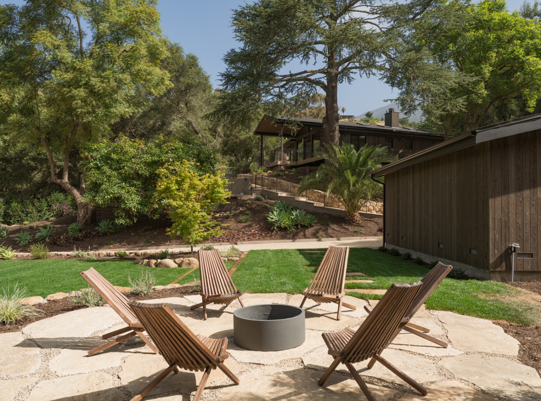 Fire-pit terrace and lawn gathered beneath mature trees