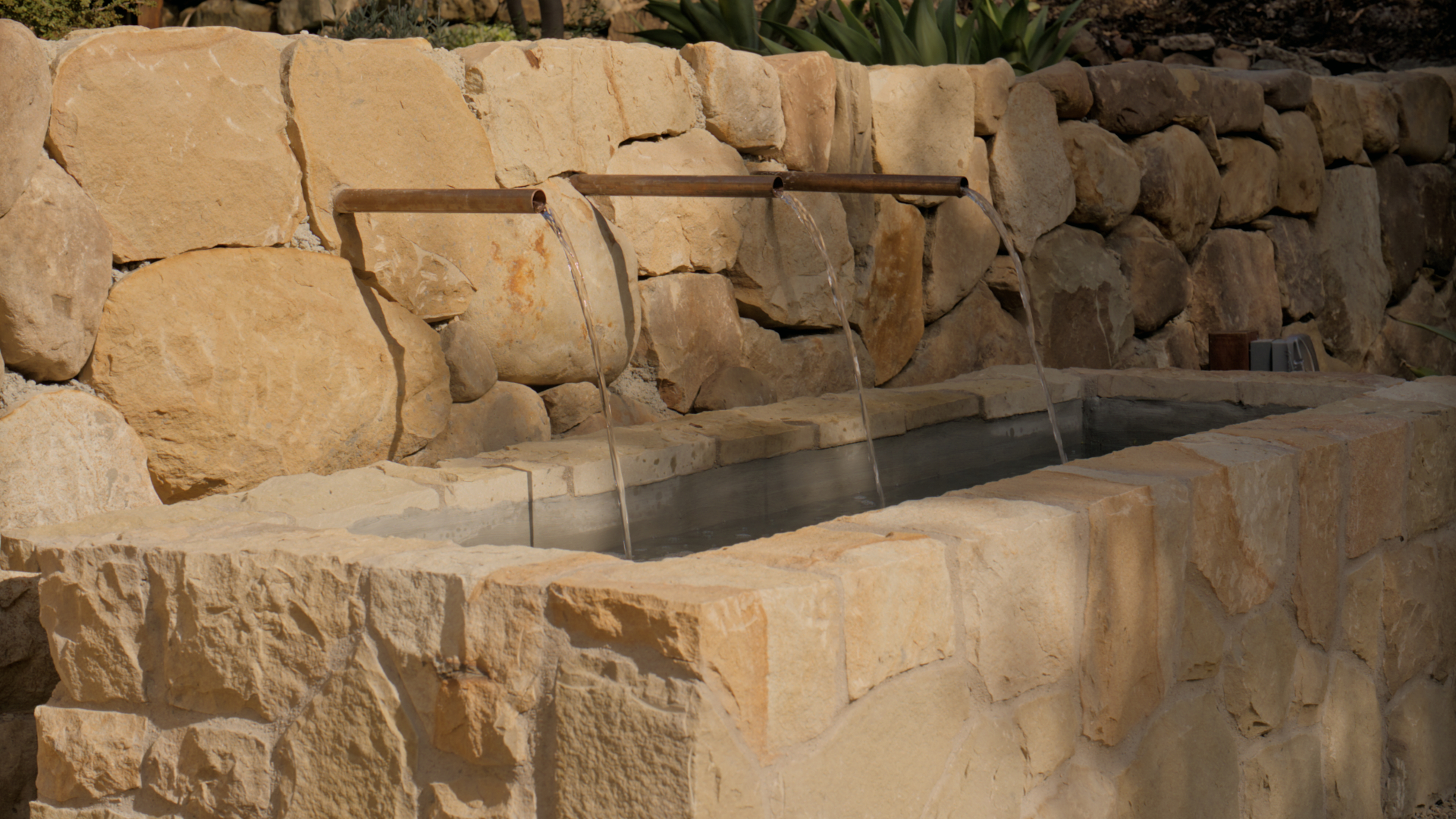 Stone fountain with copper spouts in the garden